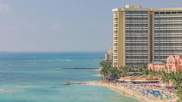 Un hôtel en bord de mer, avec plusieurs étages, une plage de sable et une vue dégagée sur l’océan.