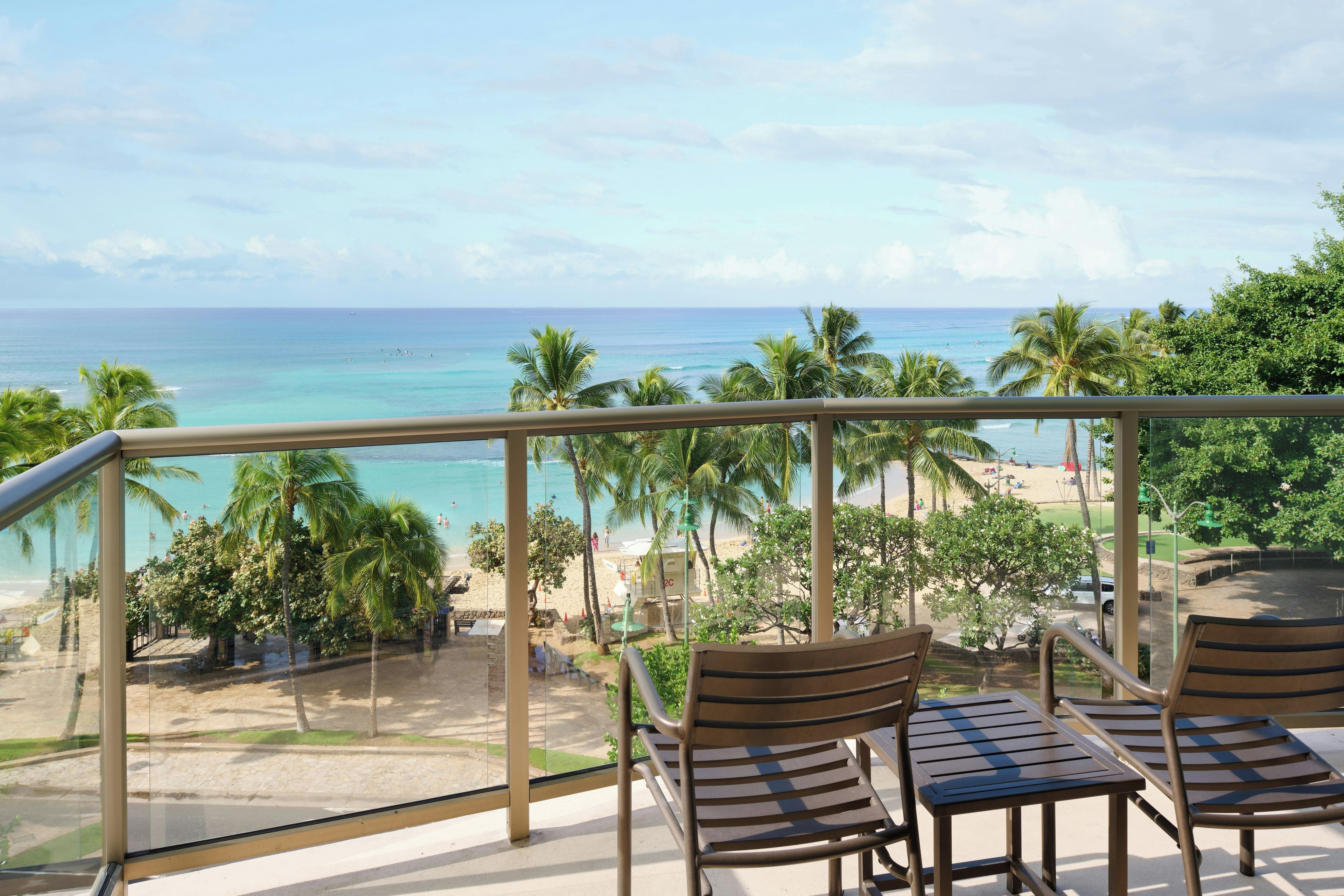Varanda com vista para a praia e oceano, com duas cadeiras e uma mesa.