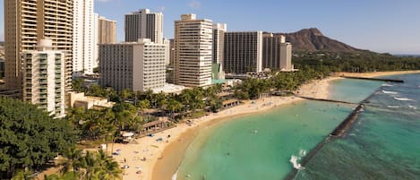 Un paisaje urbano costero con rascacielos, una playa arenosa y un océano azul y despejado.