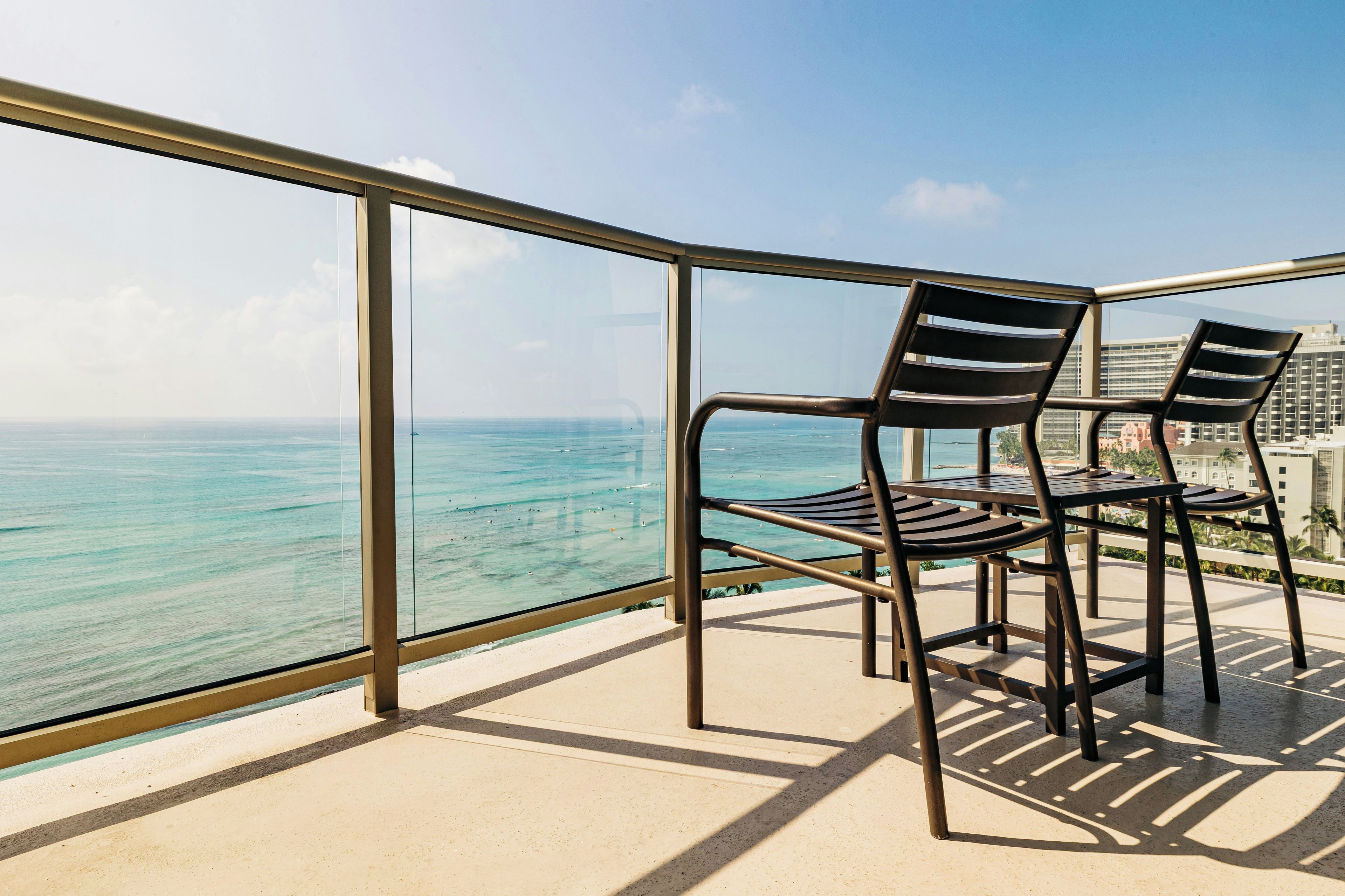 A balcony with a view of the ocean and cityscape.