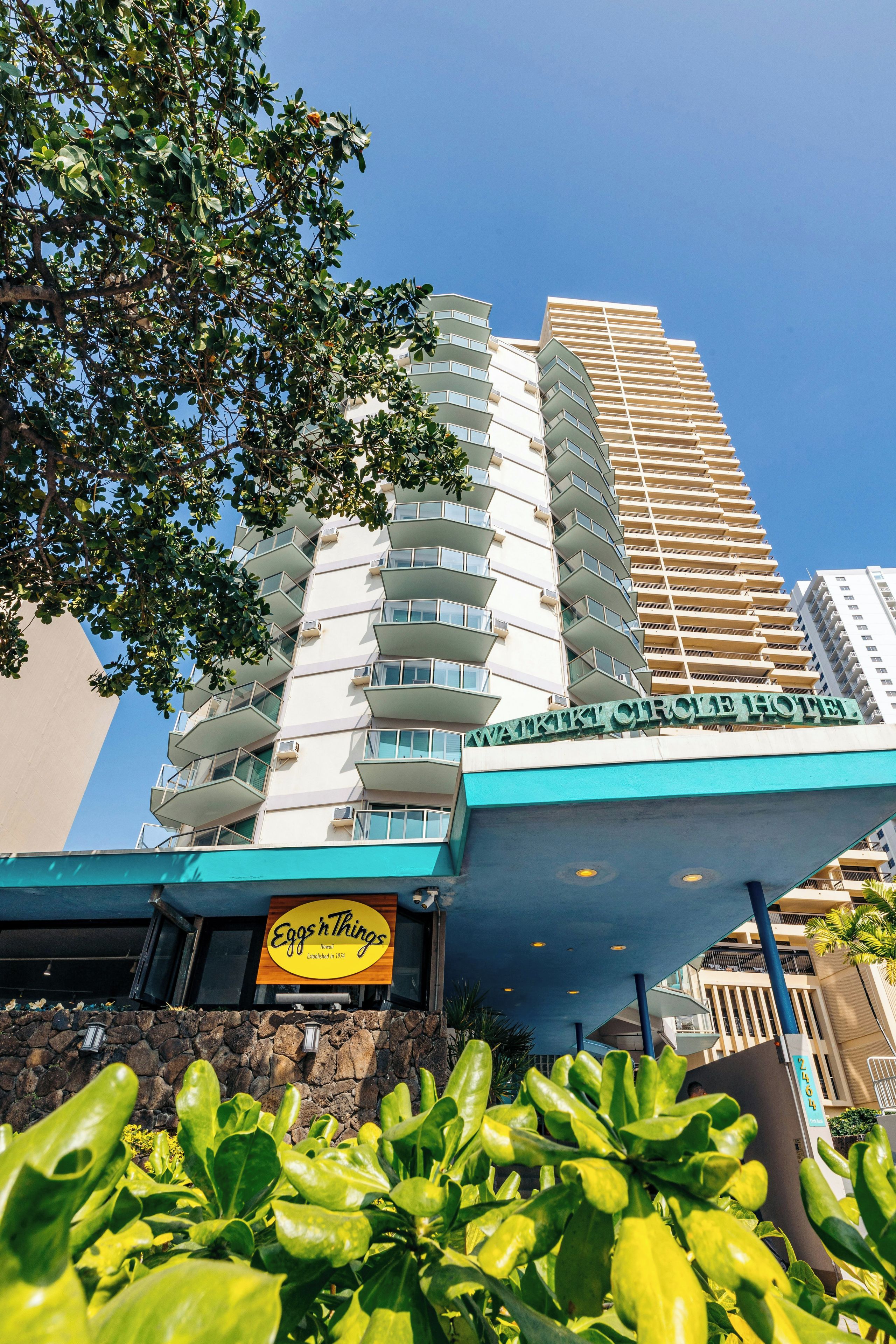 A hotel with a modern design, featuring a prominent sign for 'Watki Circe Hotel' and a restaurant named 'Eggs 'n Things.'
