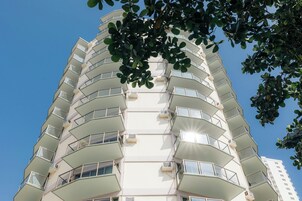 Un edificio residencial de varios pisos con balcones y unidades de aire acondicionado.