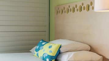 A hotel room with a bed, a nightstand, a lamp, a wall with a painting, and a window with blinds.