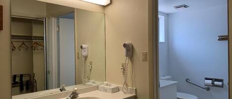 Un baño con lavamanos blanco, un espejo y un secador de pelo en la pared.