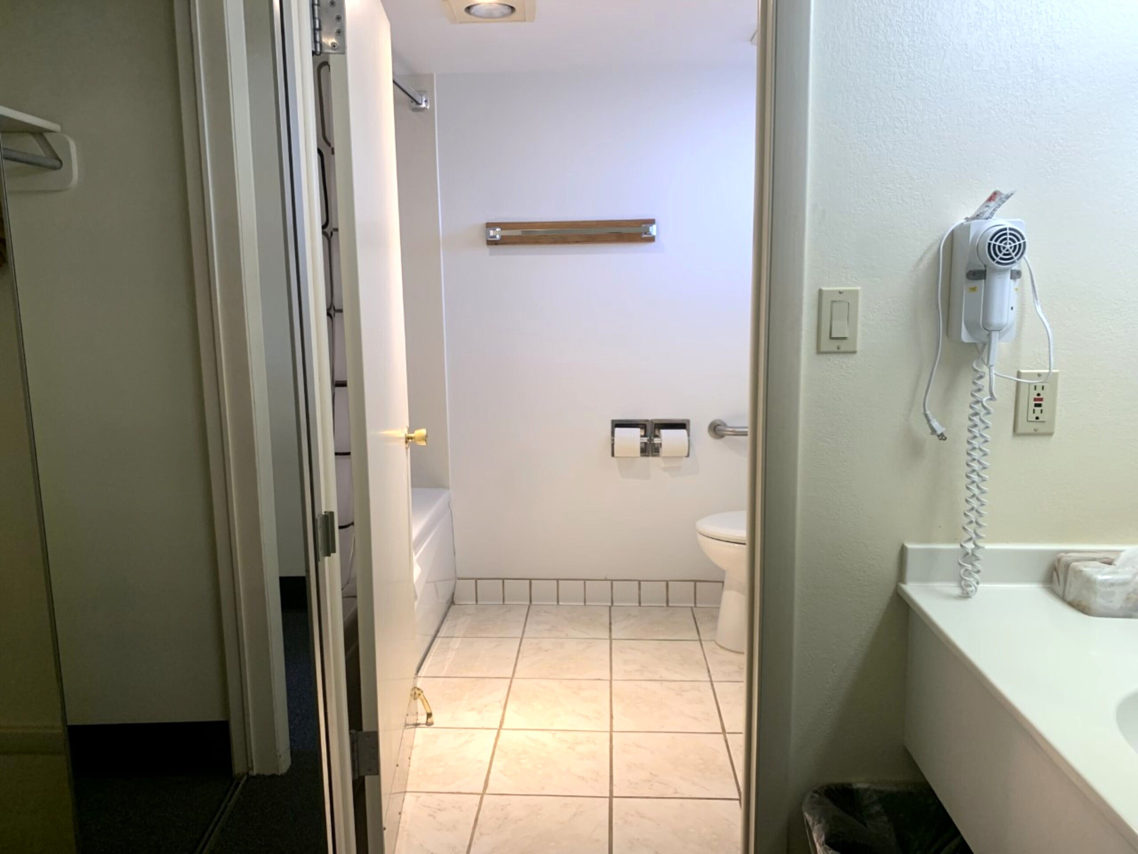 A bathroom with a toilet, a towel rack, and a hairdryer on the wall.