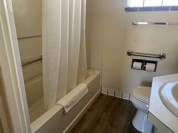 Un baño con bañera, inodoro y barra para toallas.