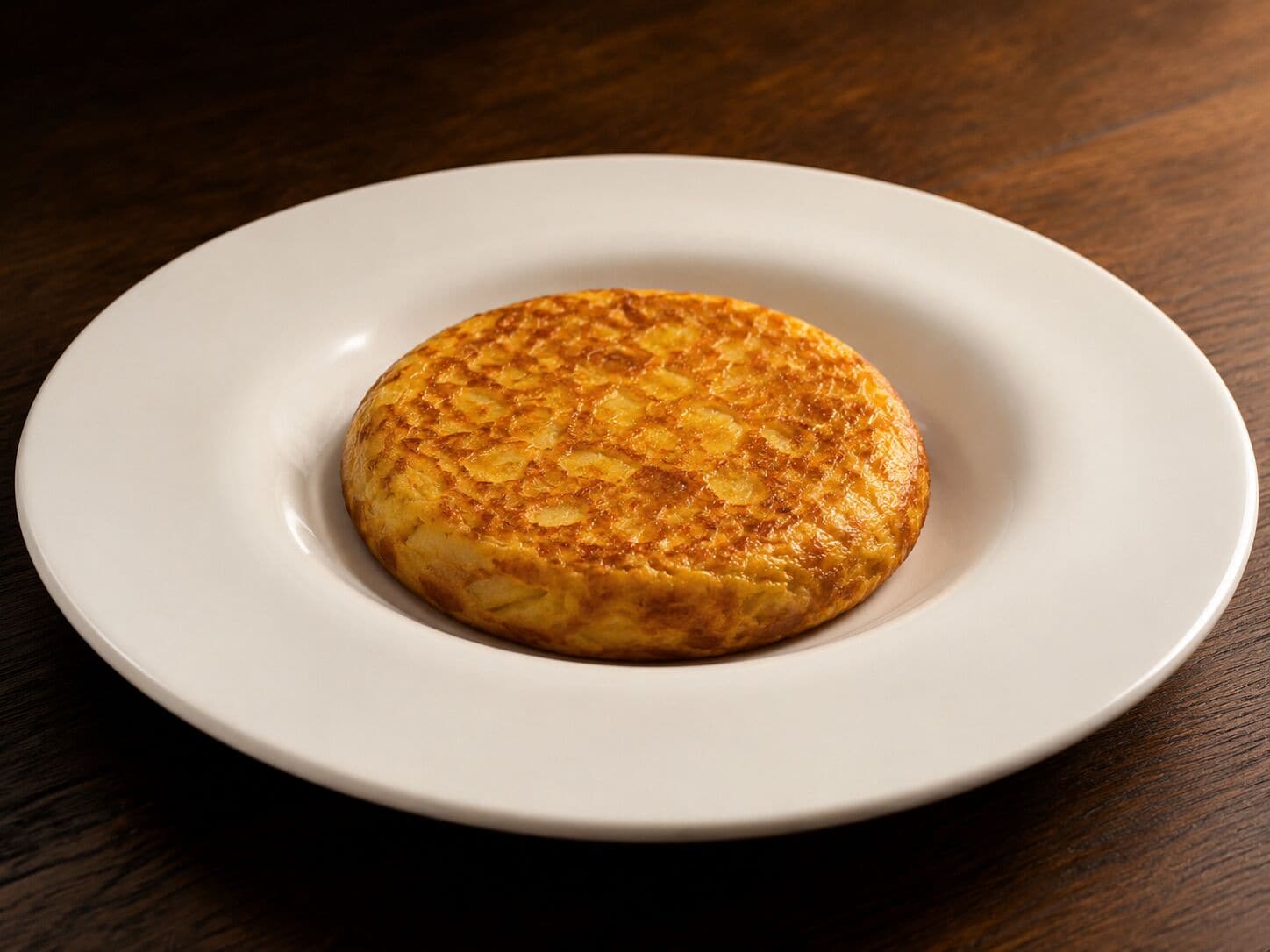 Un panqueque redondo y dorado sobre un plato blanco.