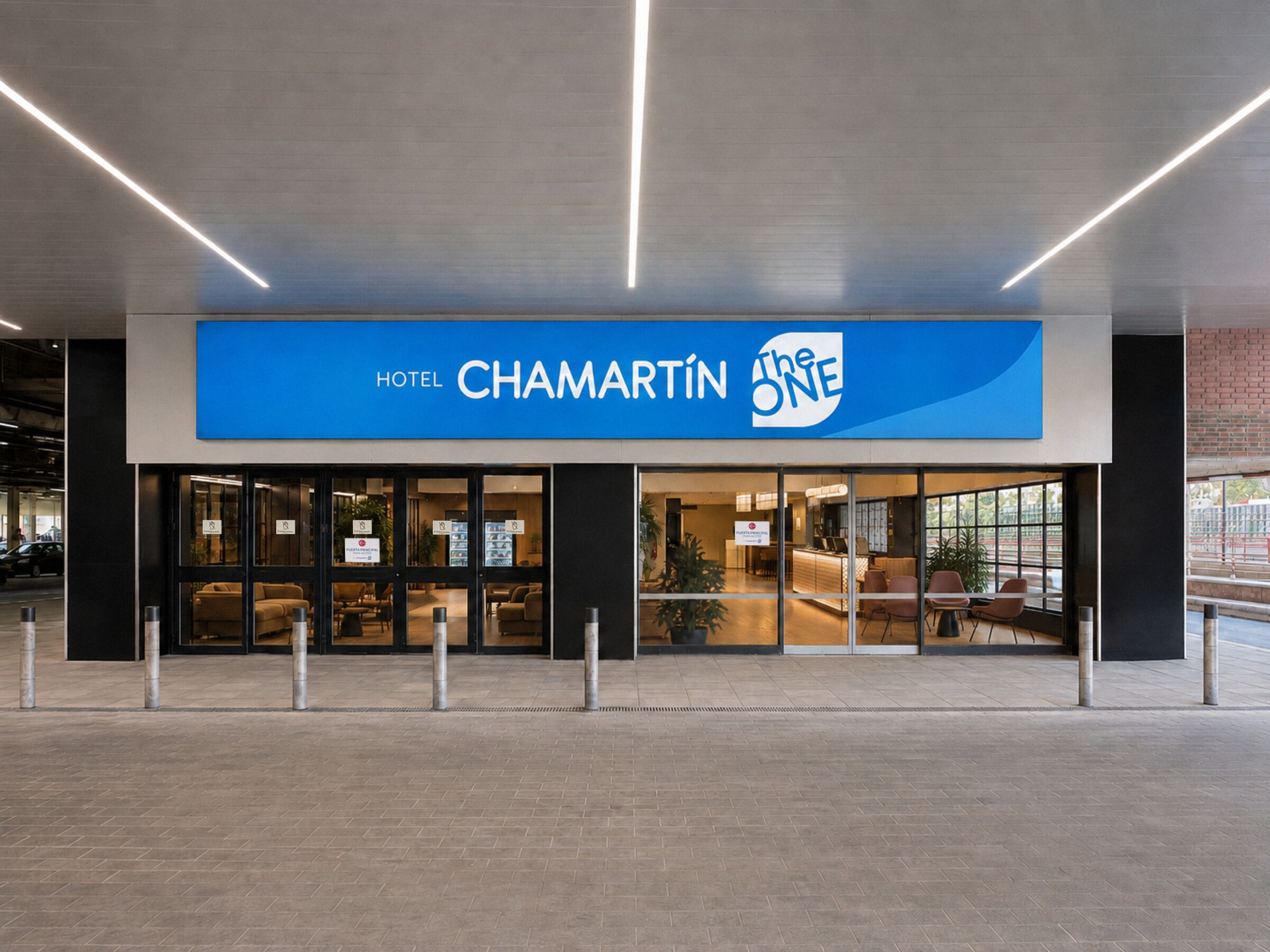 Entrada de un hotel con un letrero azul que dice 'HOTEL CHAMARTIN The ONE'.