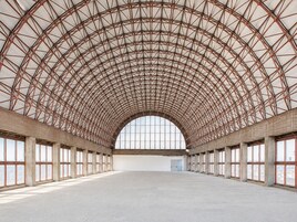 A large, open interior space with a high arched metal roof and large windows.