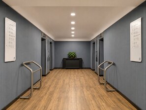 A hallway with wooden flooring, grey walls, and two elevators. - Hotel Chamartin The One (Madrid)
