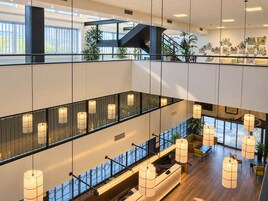 A multi-level hotel lobby with a reception desk, seating areas, and a staircase.
