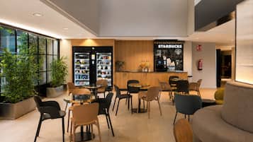 Un espacio interior moderno con mesas y sillas, un mostrador de Starbucks y un extintor en la pared.