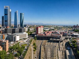 Eine Skyline mit modernen Wolkenkratzern, einem Bahnhof und der angrenzenden Stadtentwicklung.