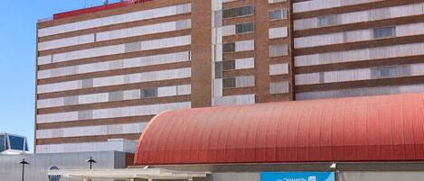 A hotel with a modern design, featuring a prominent red roof and a covered outdoor seating area.