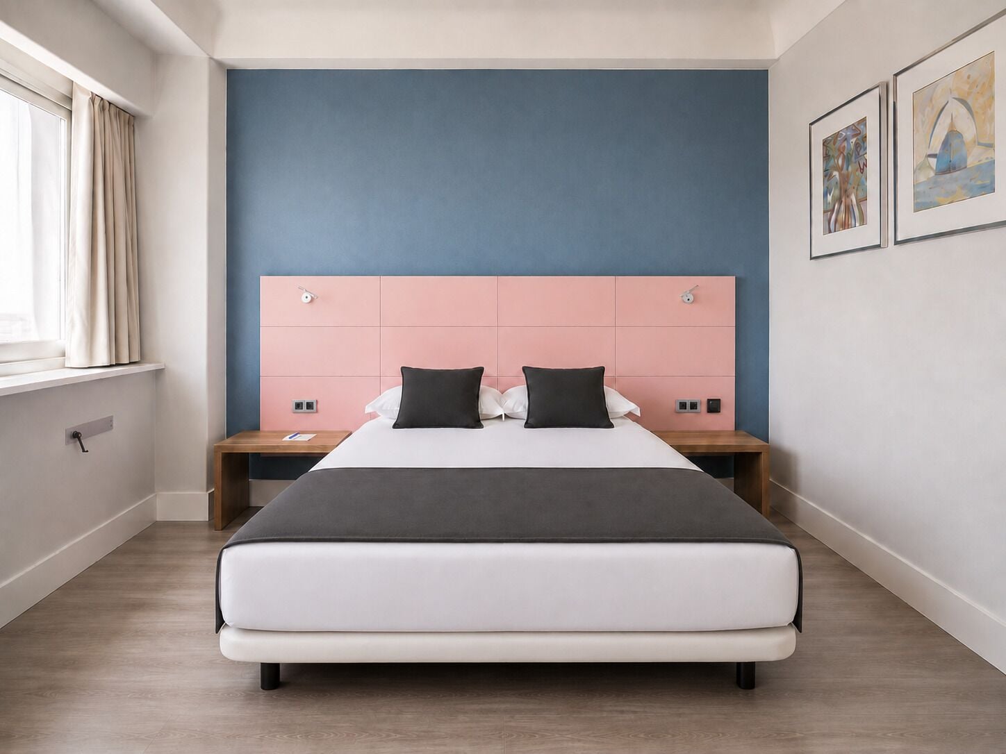 Un dormitorio moderno con una cama grande, una pared azul decorativa y obras de arte en la pared.