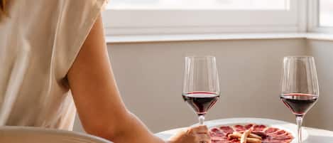 A person seated at a table with two wine glasses and a plate of food.