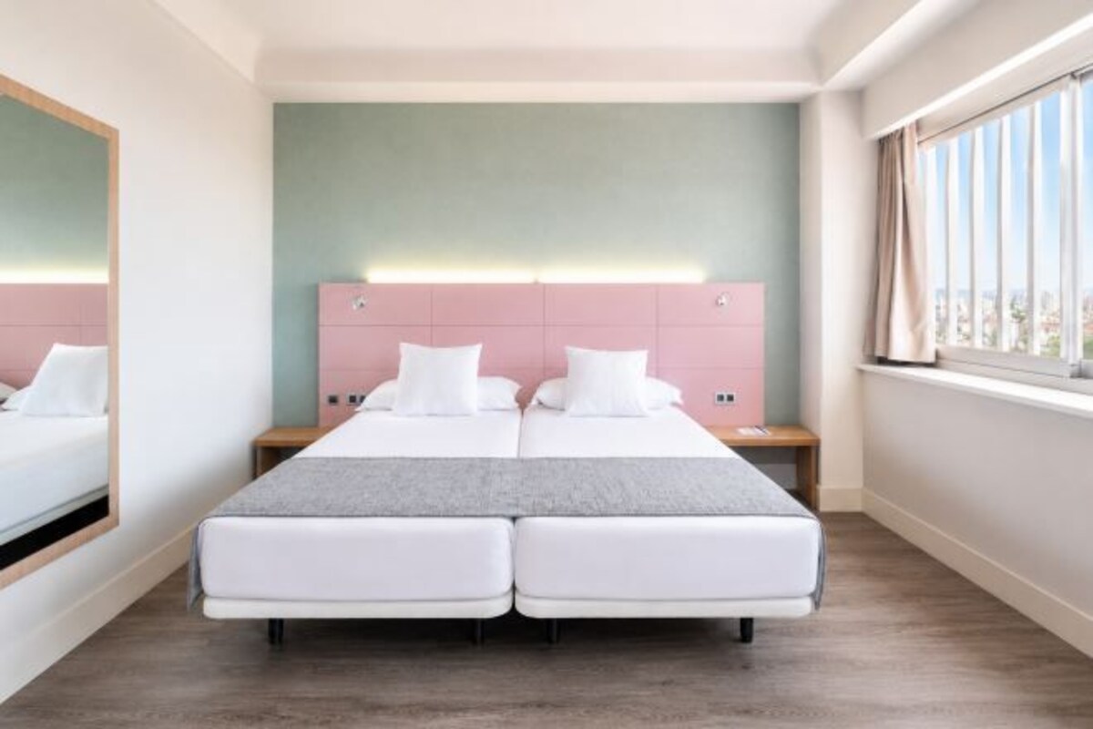 A double bed with a headboard, a bedside table, and a window with curtains.