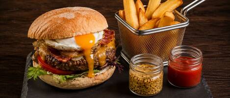 A burger with fries and condiments on a slate board.