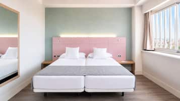 A double bed with a pink headboard, a bedside table, and a window with curtains.
