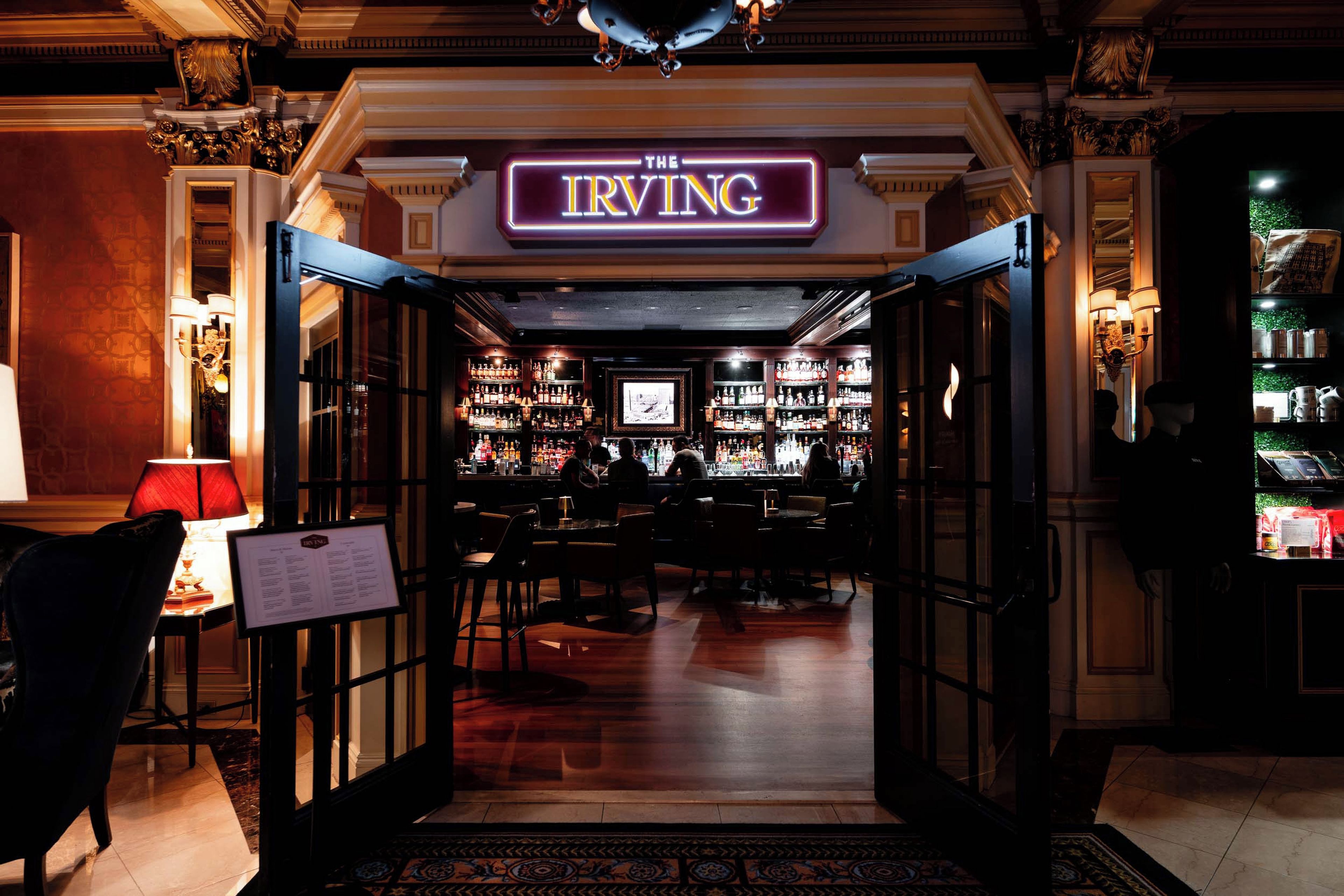 The entrance to The Irving bar with a menu board, bar area, and seating.