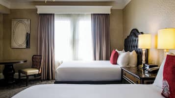 Une chambre d’hôtel avec deux lits, un bureau, une chaise, une table et un lustre.