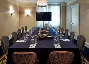 A conference room with a long table, chairs, a flat-screen TV, and wall sconces. - The Lenox Hotel Boston (Boston)