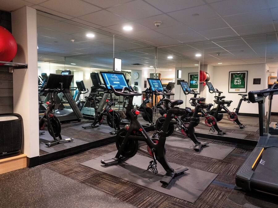 A gym with multiple exercise machines, including treadmills and stationary bikes, arranged in rows.