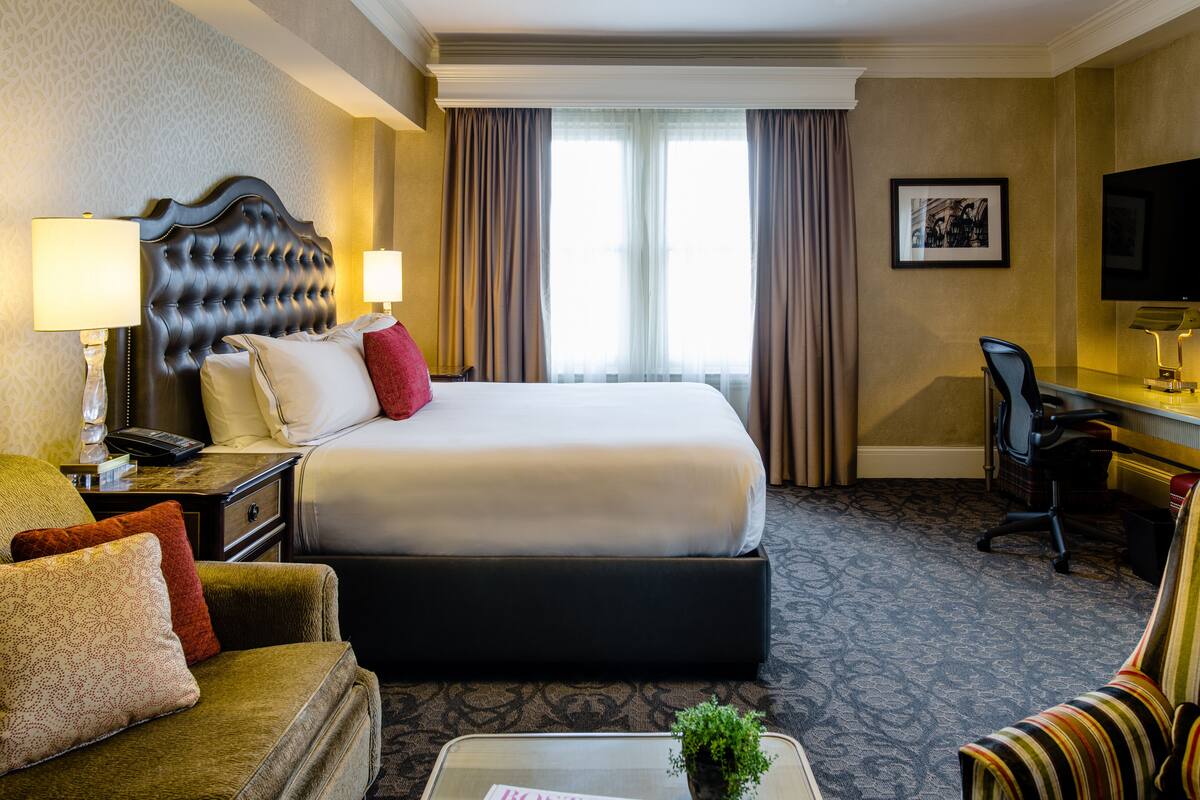 Une chambre d’hôtel avec un grand lit, un bureau avec une chaise, un canapé et un téléviseur.