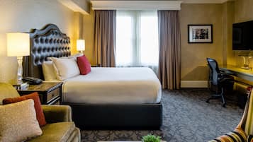 Habitació d'hotel amb un llit gran, un escriptori amb una cadira, un sofà i una televisió.