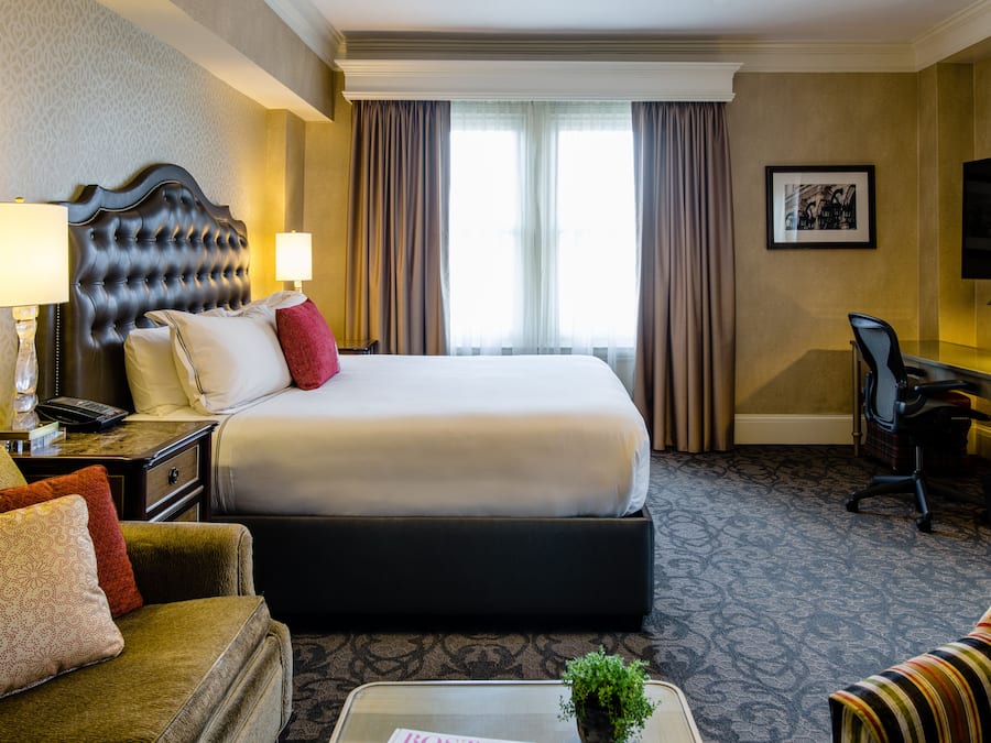 Una habitación de hotel con una cama grande, un escritorio con una silla, un sofá y un televisor.