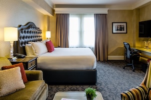Una camera d'albergo con un letto grande, una scrivania con sedia, un divano e una televisione.