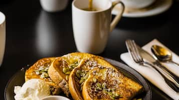 A breakfast setting with pancakes, butter, syrup, and a cup of coffee on a table.