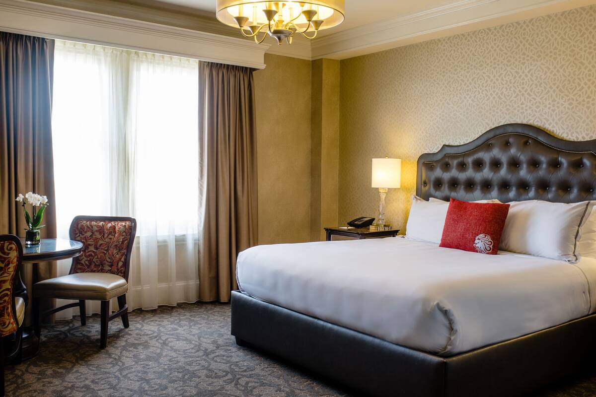 Une chambre d’hôtel avec un grand lit, une chaise, une petite table et une lampe.