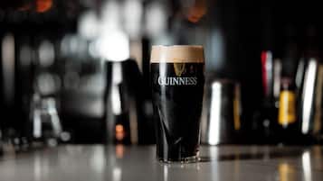 A glass of Guinness beer on a bar counter with a blurred background of bottles.