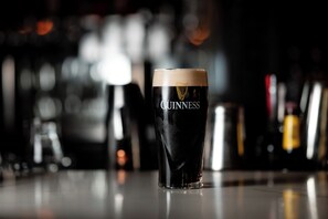 A glass of Guinness beer on a bar counter with a blurred background of bottles. - The Lenox Hotel Boston (Boston)