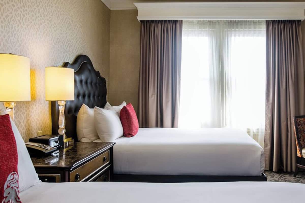 Une chambre d’hôtel avec deux lits, un bureau, une chaise et une table à manger.