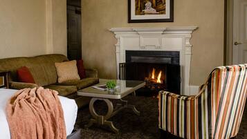 A cozy living room with a fireplace, a sofa, a striped armchair, and a coffee table.