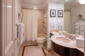 A bathroom with a toilet, shower, sink, and mirror.