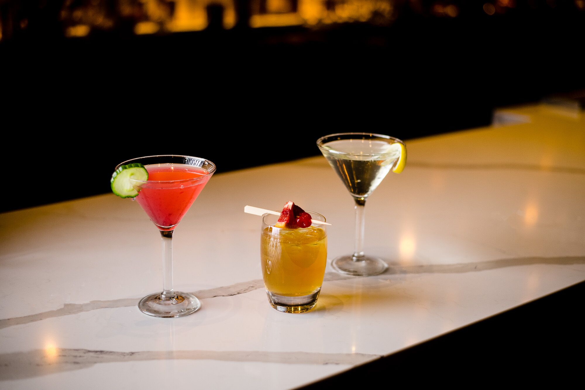 Drei Cocktails auf einer Marmor-Theke.