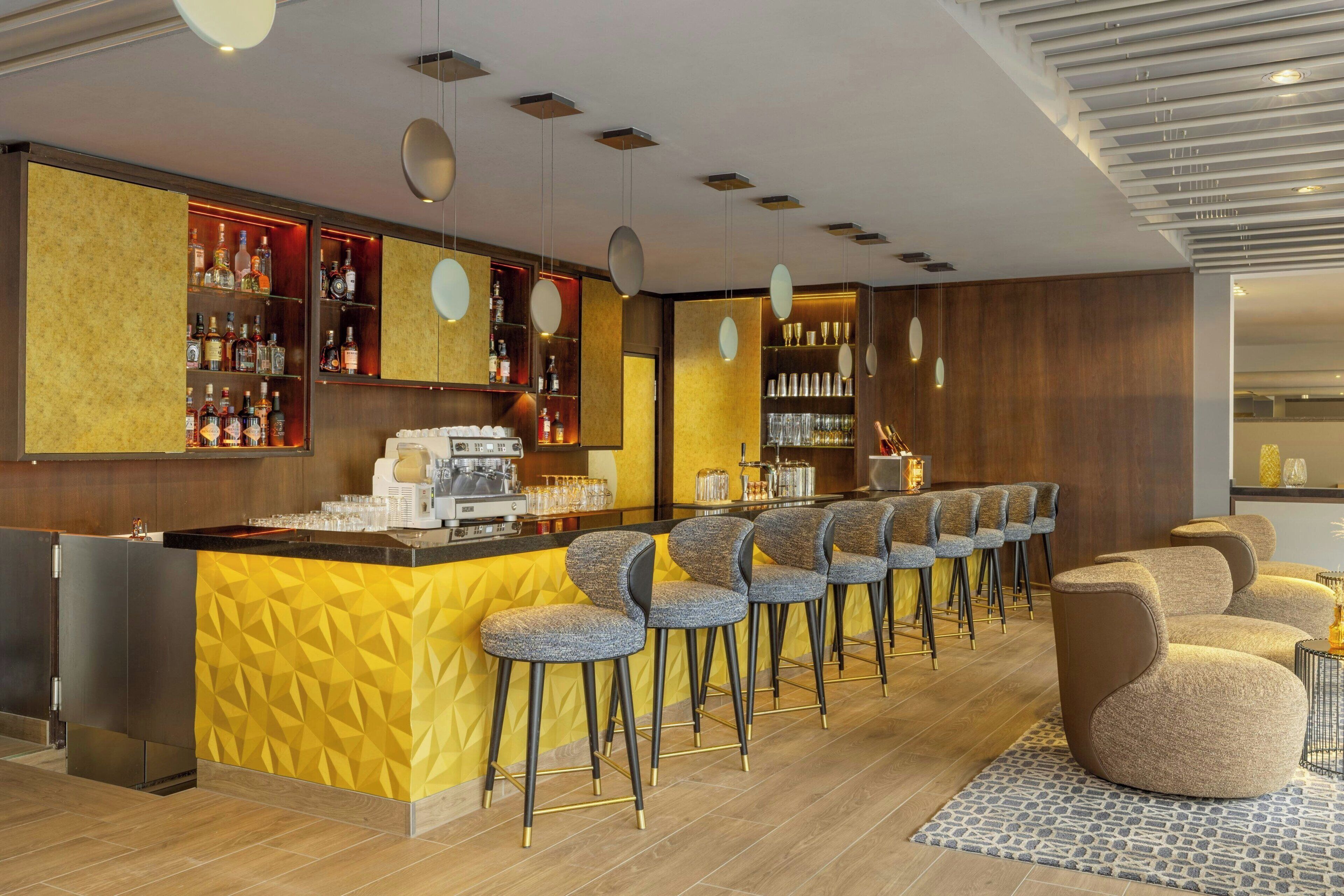 Zona de bar moderna con una pared de acento amarilla, taburetes y una máquina de café.