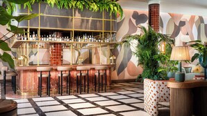 A bar area with a checkered floor, bar stools, and a variety of bottles on shelves.