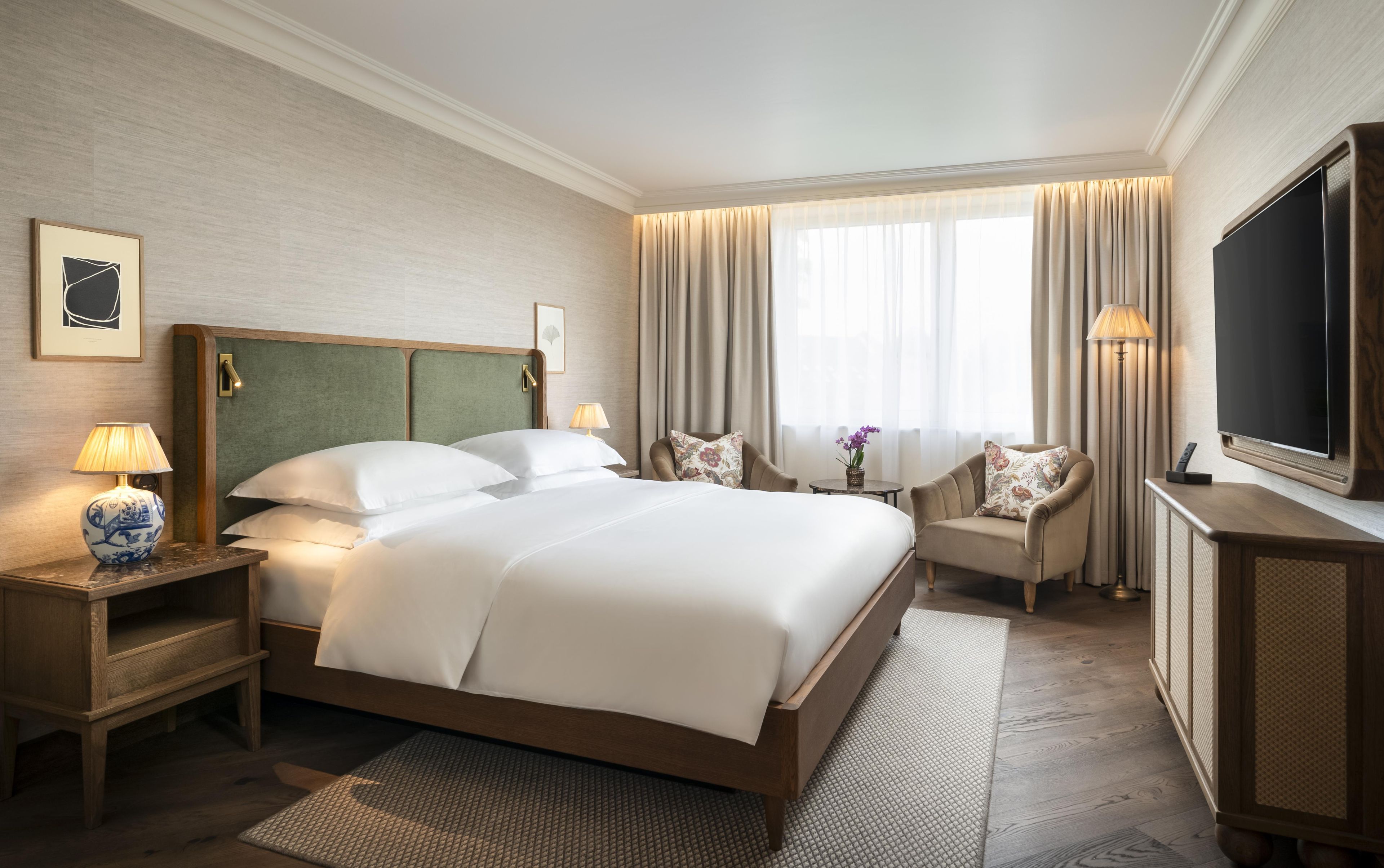 Habitación de hotel con una cama grande, televisión, escritorio y silla.
