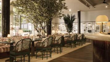 A hotel lobby with a seating area, a large tree, and a bar.