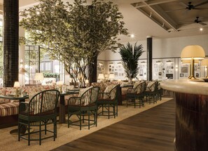 A hotel lobby with a seating area, a large tree, and a bar.