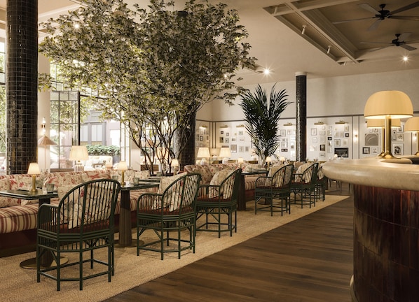 A hotel lobby with a seating area, a large tree, and a bar.