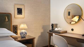 Ein Hotelzimmer mit einem Bett, einem Schreibtisch mit Lampe, einer Kaffeemaschine und einem Spiegel.