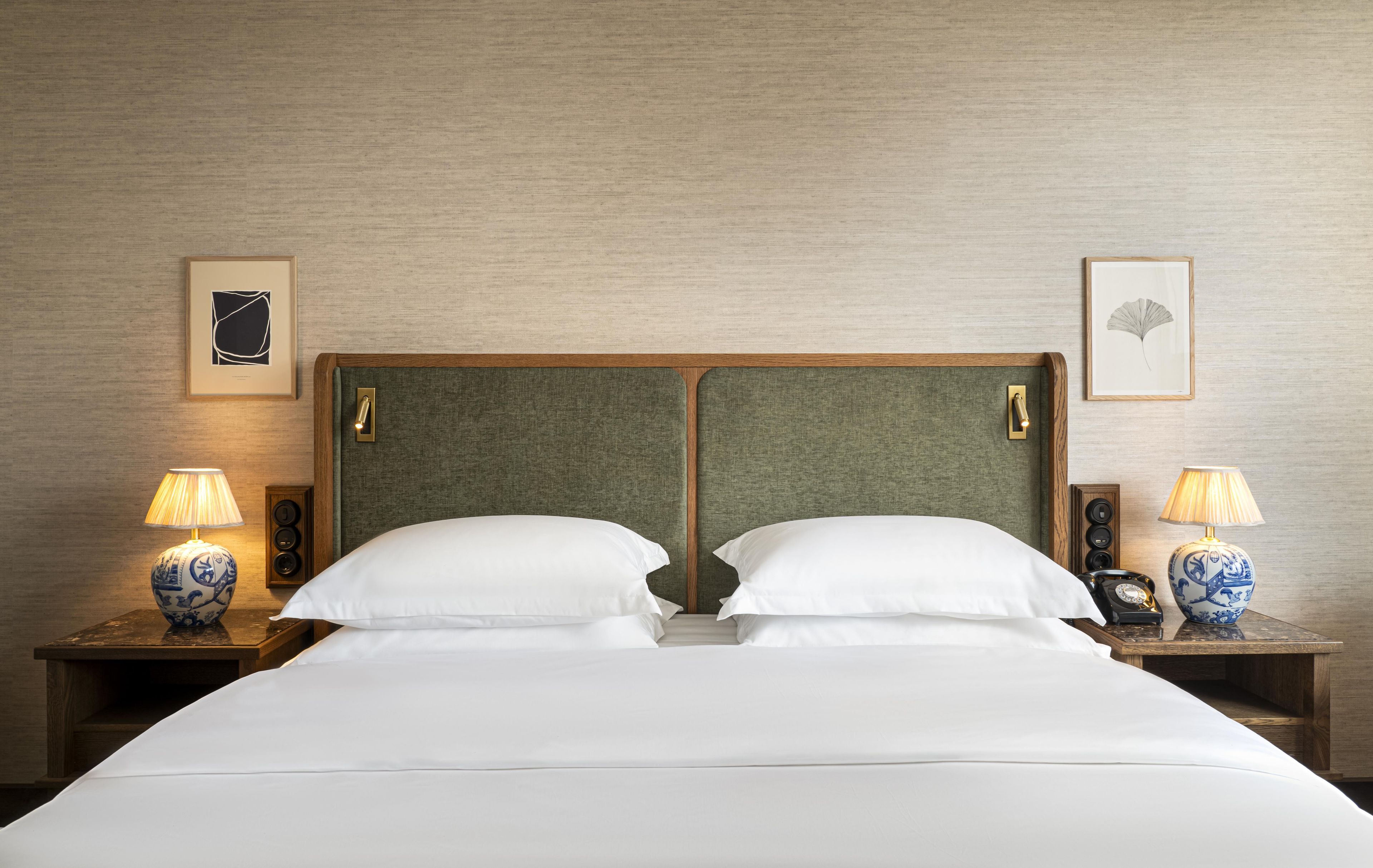 A hotel room with a double bed, two bedside tables with lamps, and framed artwork on the walls.