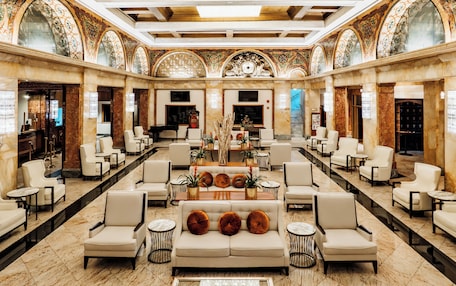 A spacious lobby with a central sofa, multiple seating areas, and a decorative ceiling.