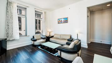 Una sala moderna con un conjunto de sofá, una mesa de centro y dos lámparas. Hay un cuadro en la pared y una ventana con cortinas.