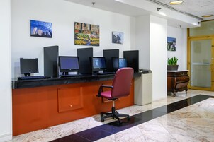 Una recepción con varios monitores de computadora, una silla de oficina roja y obras de arte en las paredes.